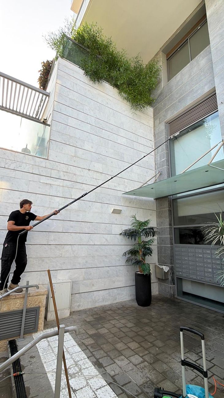 איתי מנקה חלונות בגובה עם מוט אוסמוזה הפוכה